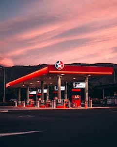 A gas station illuminated under vibrant sunset skies in Nelson, New Zealand.