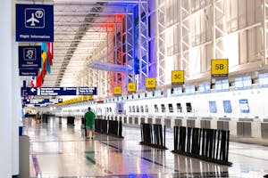 Wide view of Chicago airport terminal showcasing architecture and check-in counters. Flags and signages add vibrant detail.